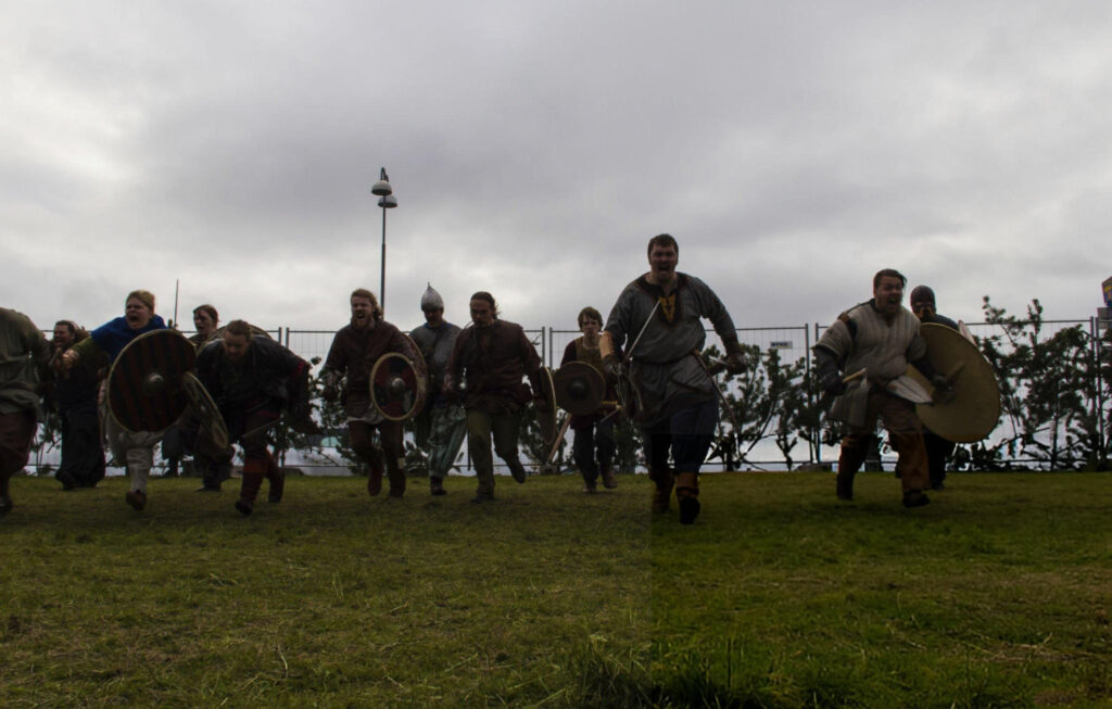 Anglo-Saxon soldiers defending a fortified Wessex town against Viking invaders, with shields raised and swords drawn.