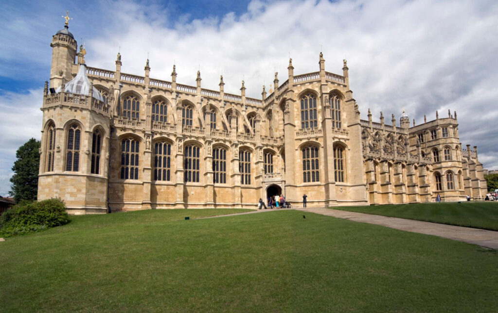 A panoramic view of Windsor Castle, featuring its iconic towers and battlements against a clear blue sky.