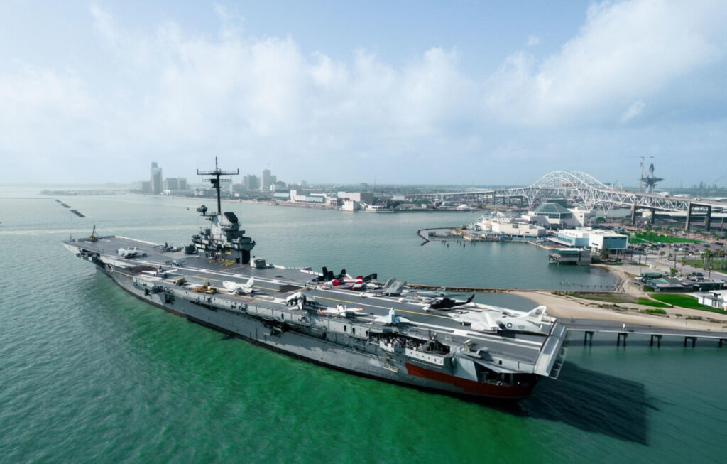 A historic photograph of the USS Lexington (CV-2) during World War II, showcasing her aircraft on deck and naval crew.