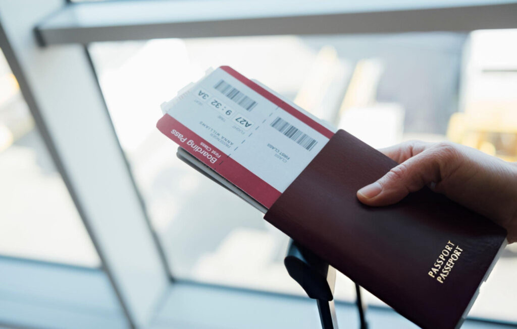 A man seated in a luxurious airplane first-class cabin, holding a boarding pass and smiling, representing Steven Rothstein's lifetime AAirpass adventure.